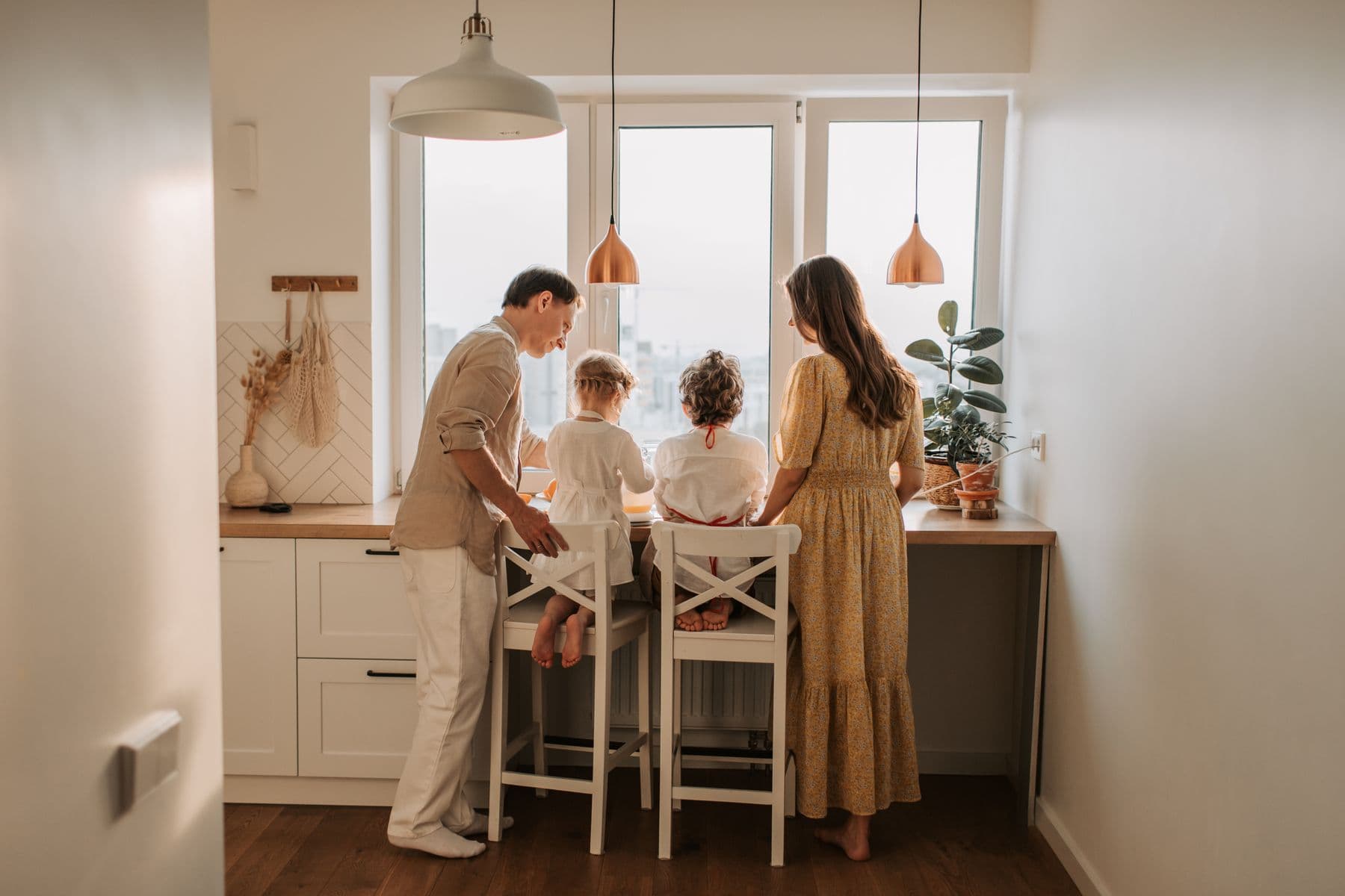 Two adults and two children together at a kitchen counter, viewed from behind